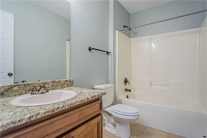Polished granite countertops and classic wood cabinetry anchor this functional full bathroom.