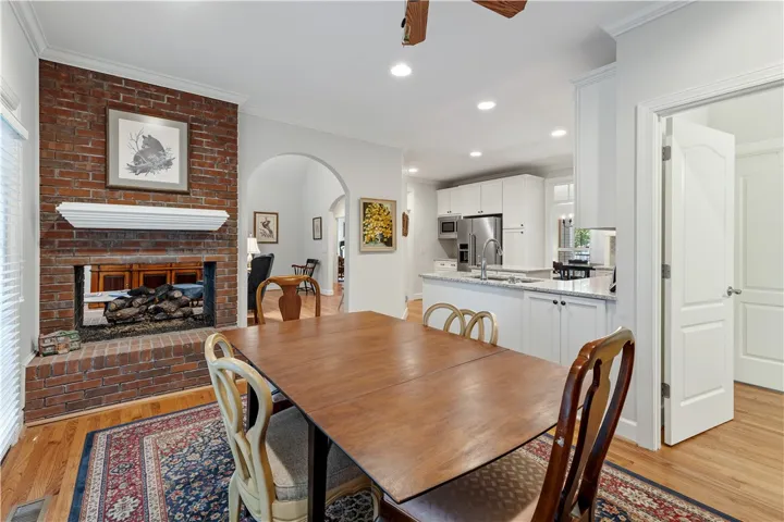 Warm hardwood floors complement a classic brick fireplace in this inviting dining area.