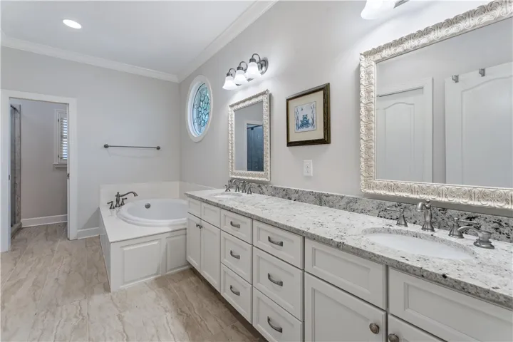 A refined bathroom features stone-patterned tile floors, granite counters, and a soaking tub.