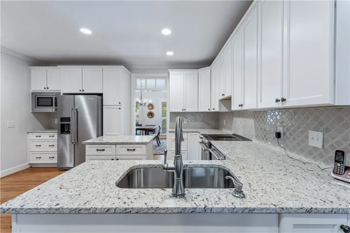 Polished stone countertops pair seamlessly with classic cabinetry and sleek wood flooring.