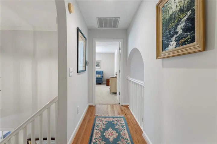 Rich hardwood flooring anchors the upper hallway, which is accented by classic architectural archways.