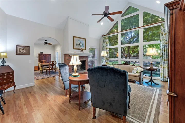 Hardwood floors and a brick fireplace anchor this living room under a vaulted ceiling.