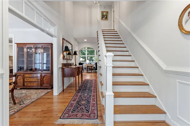 An inviting entryway presents classic wood flooring, detailed wainscoting, and a prominent staircase.