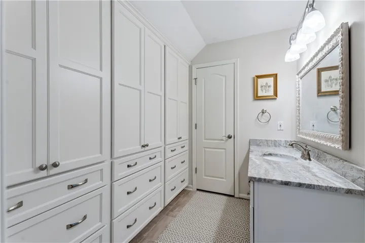 Custom cabinetry and polished stone countertops elevate this functional washroom.