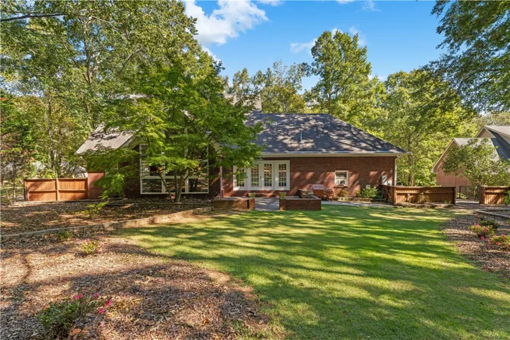 Mature trees frame the classic brick exterior and manicured lawn of this inviting backyard.