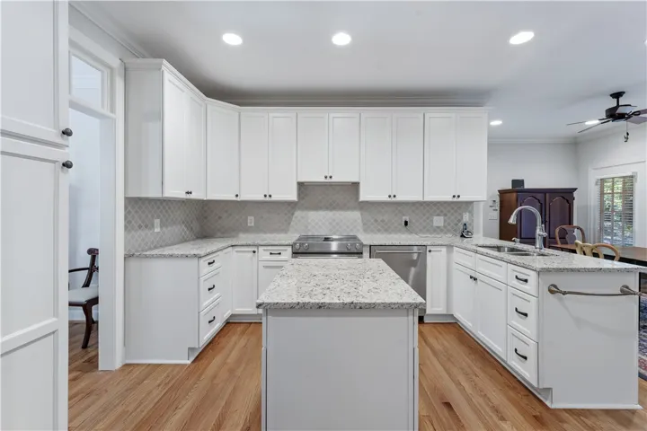 Polished stone counters and pristine white cabinetry define this beautifully appointed kitchen workspace.