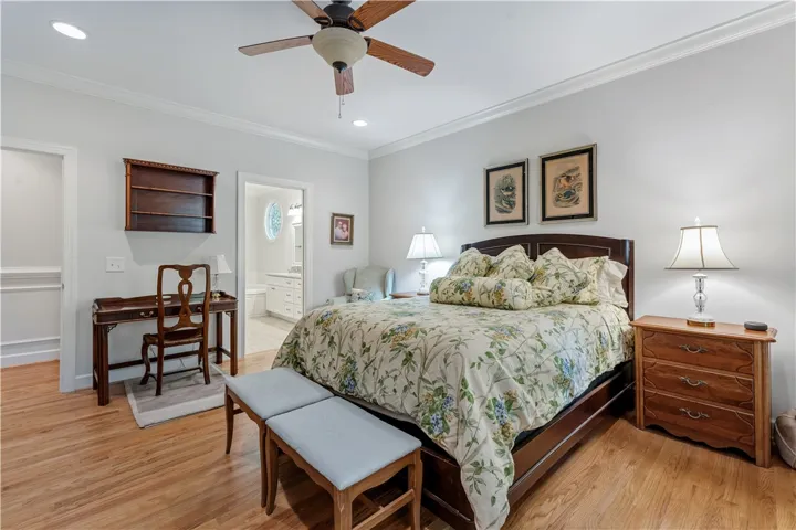 Gleaming hardwood floors and classic crown molding define this serene bedroom space with adjacent bath.