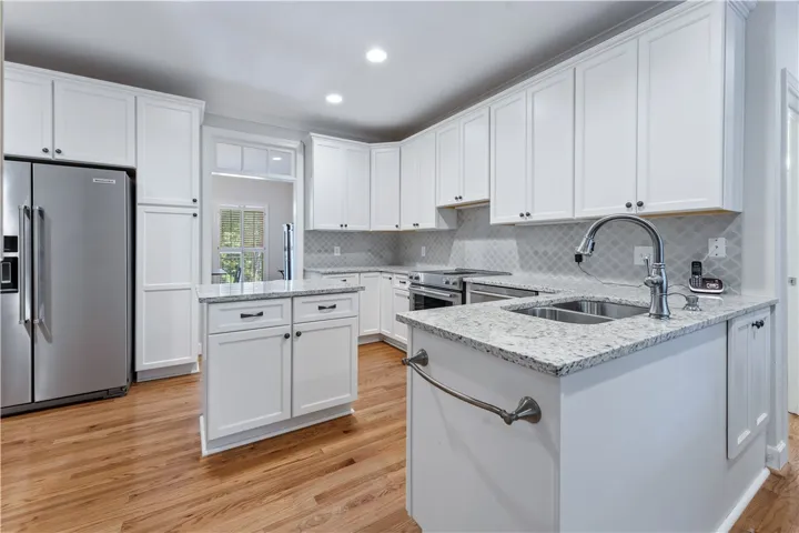 Gleaming hardwood floors complement white cabinetry and polished stone countertops in this modern workspace.