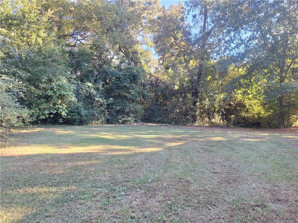 Mature trees frame a grassy lawn, creating a serene and private outdoor environment.