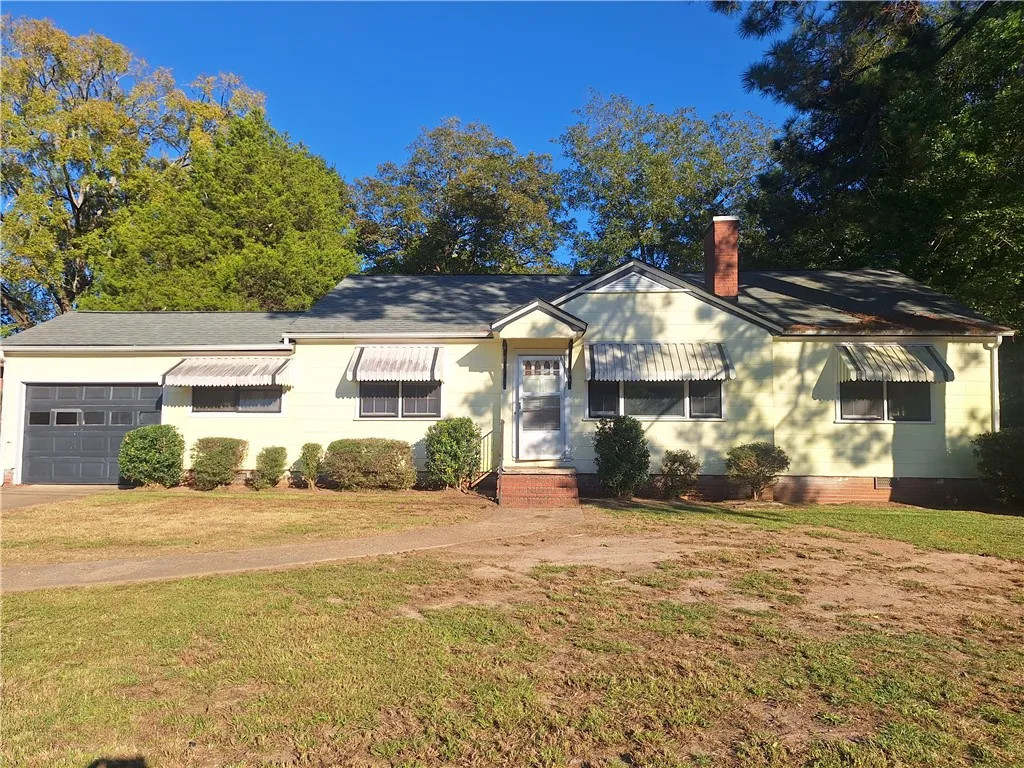 A classic ranch exterior showcases vintage awnings and a brick entryway under mature trees.