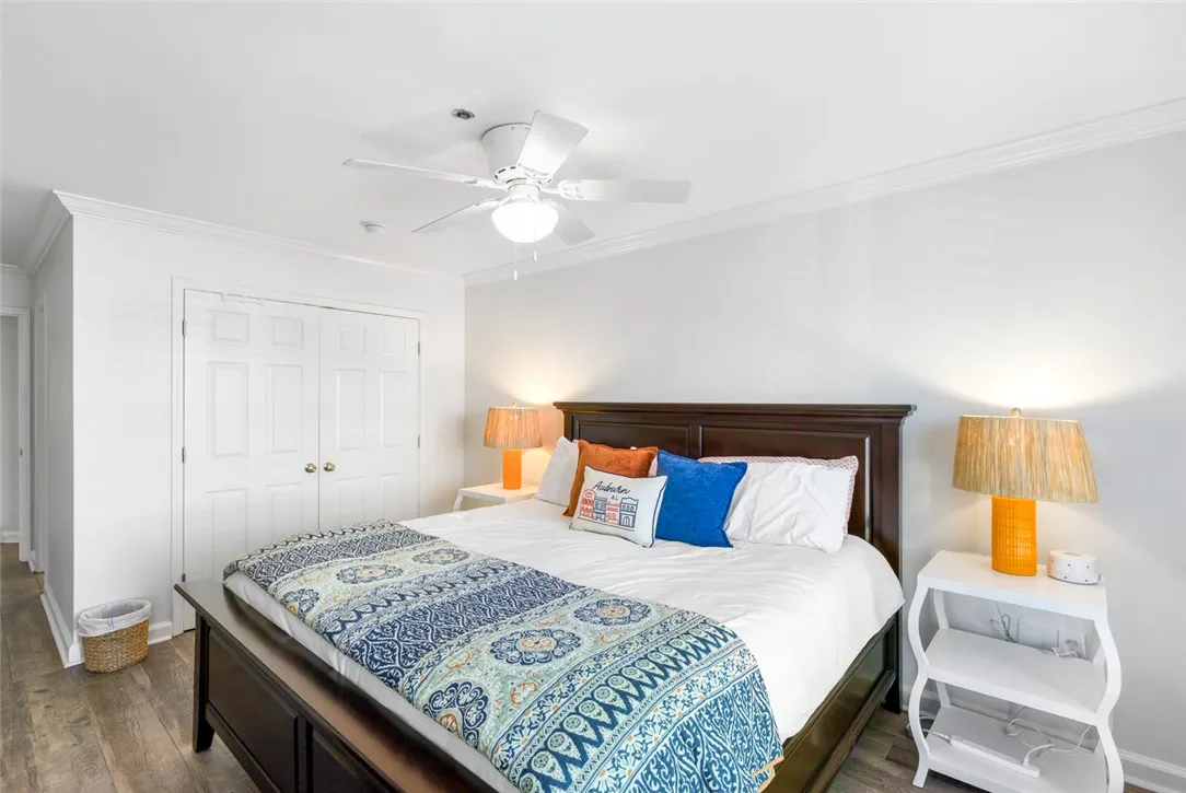 Rich wood floors and elegant crown molding elevate this serene and comfortable bedroom space.