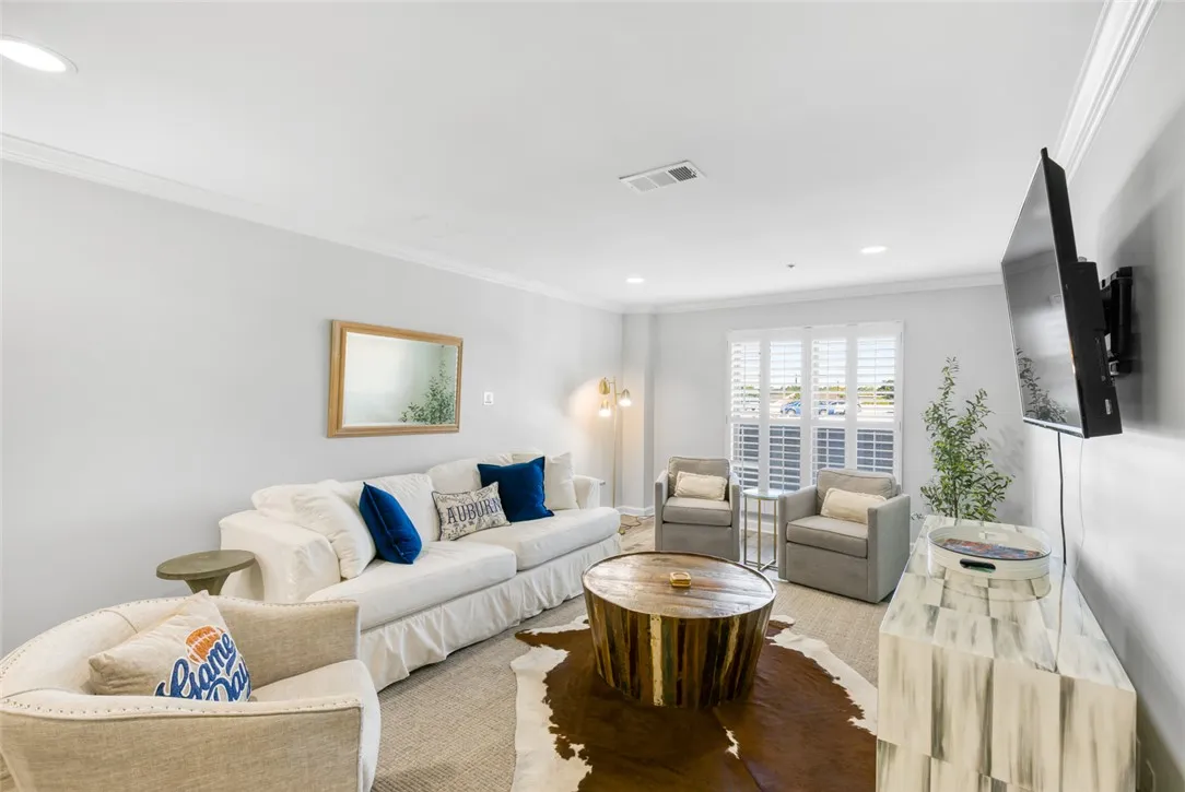 An inviting open layout features clean crown molding, recessed lighting, and timeless plantation shutters.