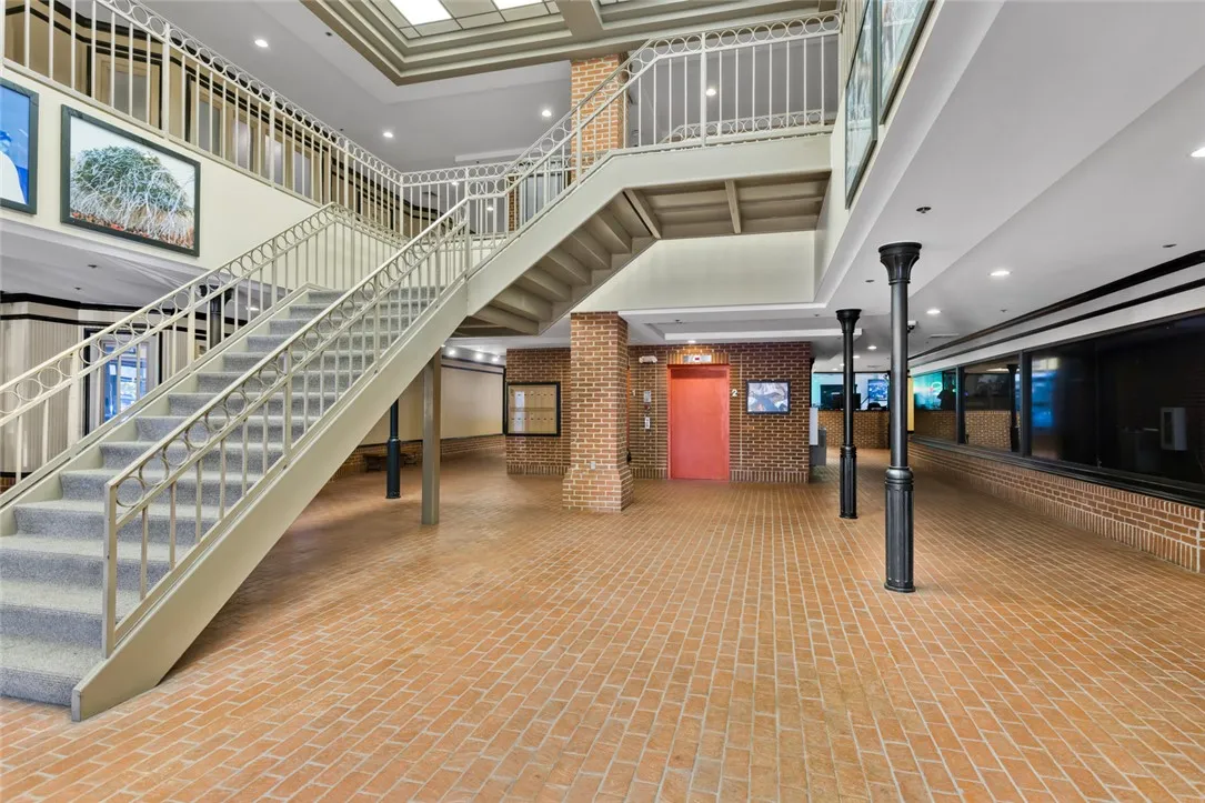 An open multi-level lobby features distinctive brick flooring and a central stairwell.