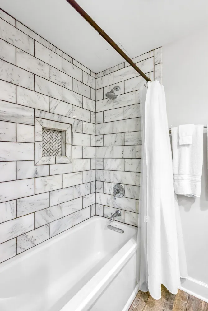 Elegant marble subway tile surrounds a soaking tub accented by textured wood flooring.