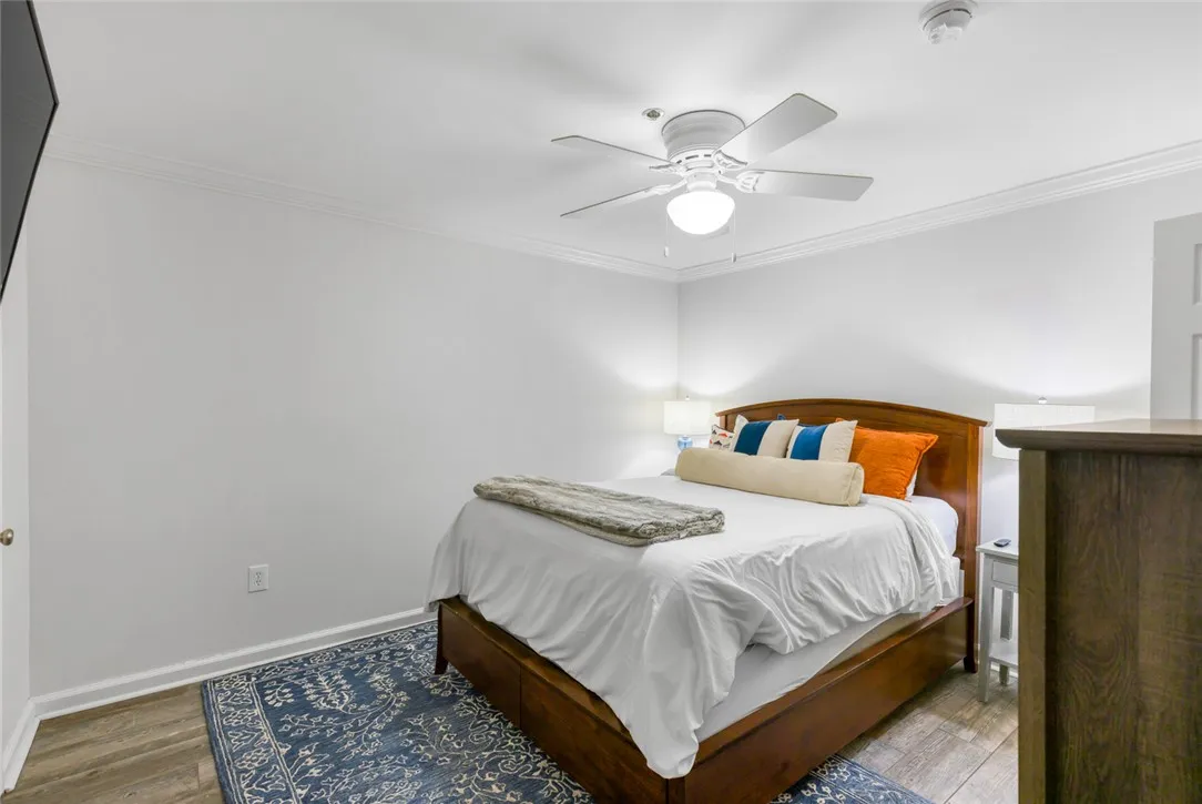 Crown molding frames this comfortable bedroom space detailed with classic wood-look flooring.