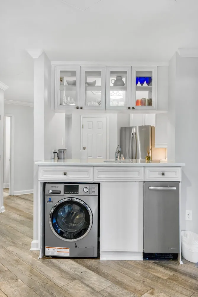 A well-integrated wet bar features glass-front cabinetry, stone counters, and durable wood-look flooring.