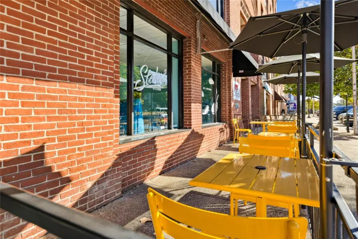 Classic brick architecture frames a welcoming outdoor patio space set along the sidewalk.