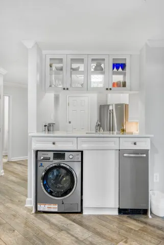 A well-integrated wet bar features glass-front cabinetry, stone counters, and durable wood-look flooring.