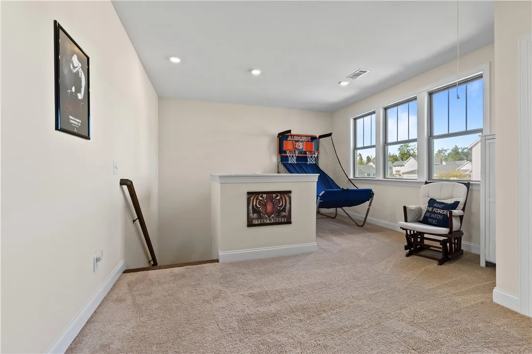 Sunlight streams through large windows into this versatile carpeted loft space with recessed lighting.