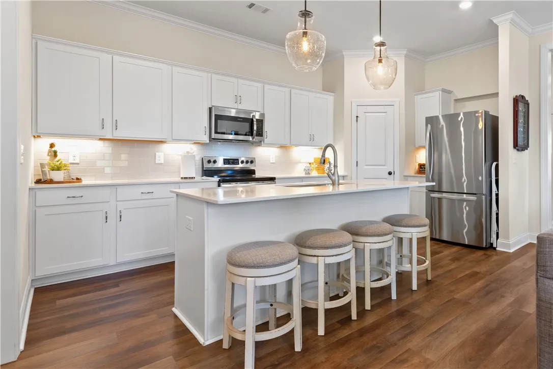 Elegant kitchen with walk-in pantry, under cabinet lighting & shaker cabinetry.