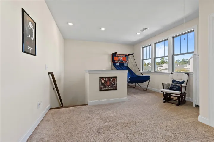 Sunlight streams through large windows into this versatile carpeted loft space with recessed lighting.