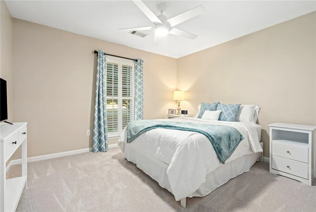 Plush carpeting underfoot and plantation shutters frame a quiet, comfortable bedroom retreat.