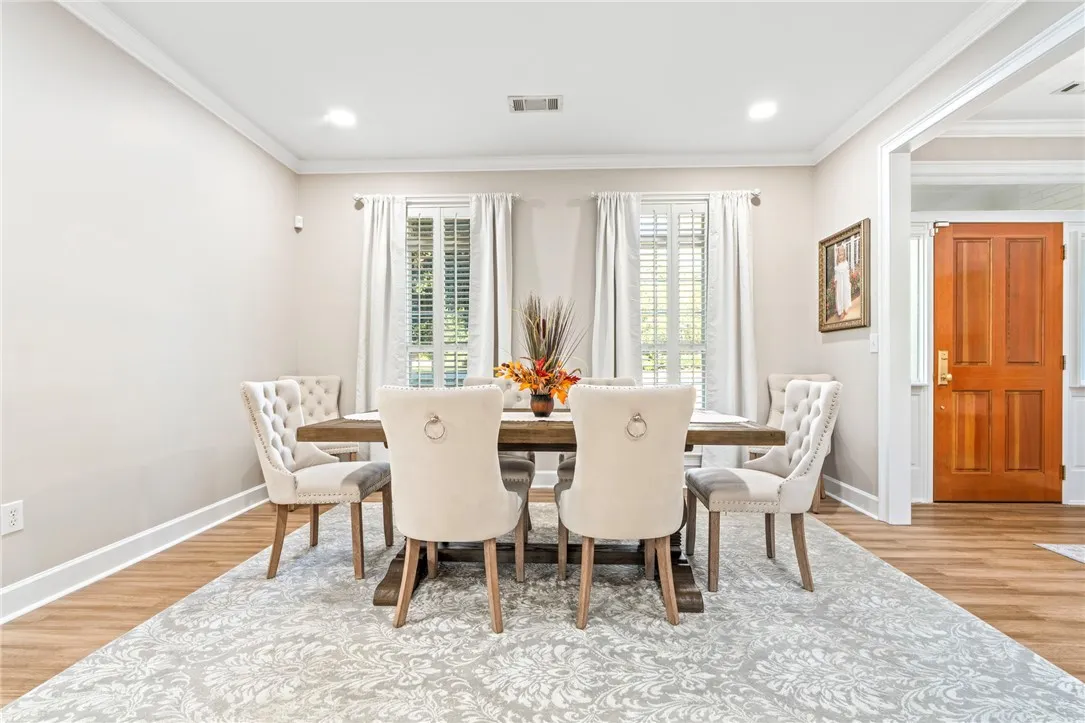 Elegant crown molding complements clean lines and warm wood-style flooring in this classic dining space.