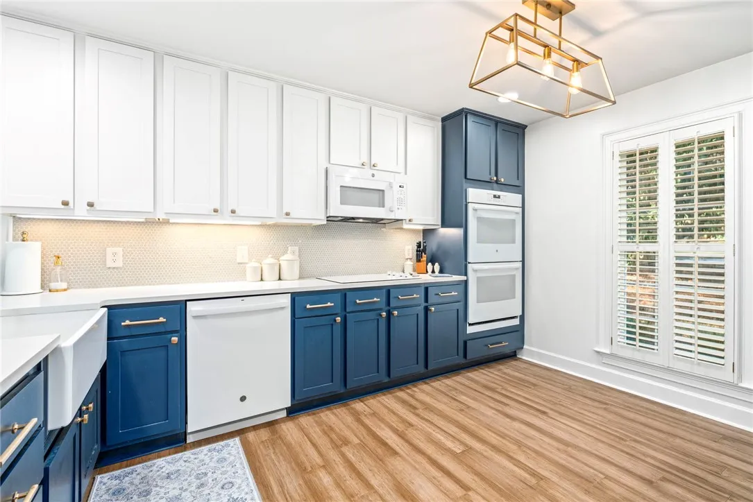 Contrasting two-toned cabinetry and handsome wood flooring define this updated kitchen space.