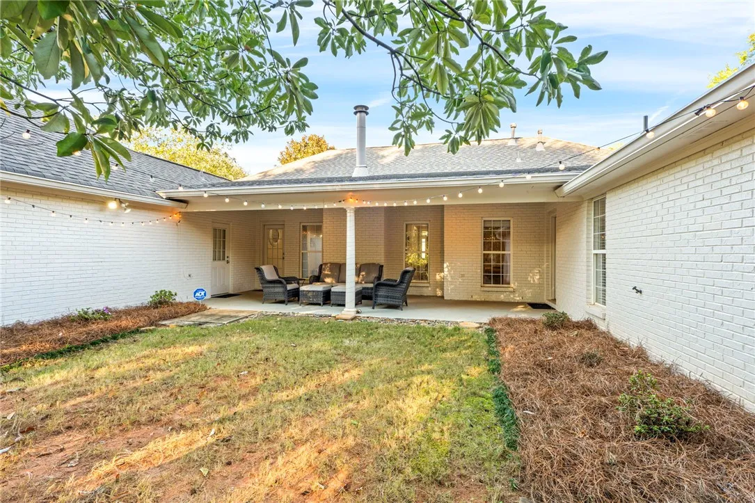 A covered back patio overlooks the yard, framed by classic painted brick walls.