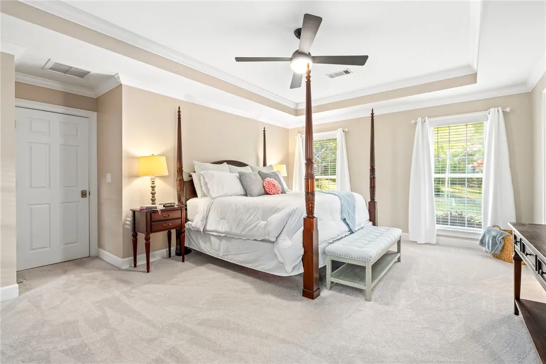 Crown molding and a tray ceiling frame this spacious suite featuring plush carpet flooring.