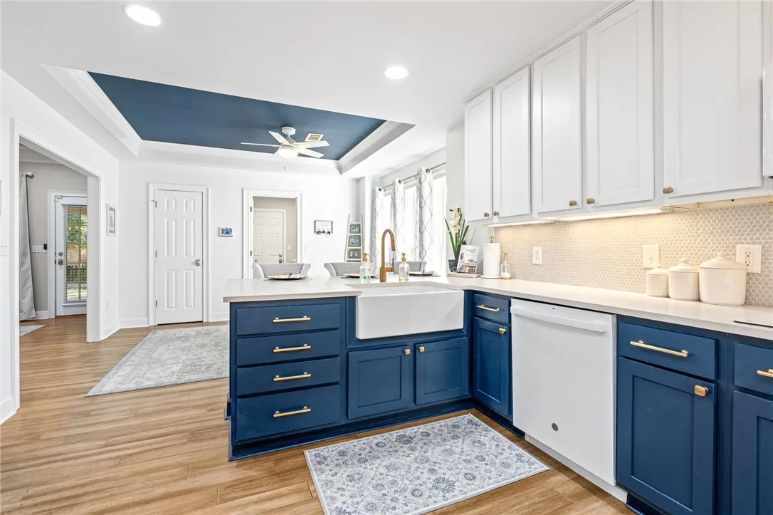 Modern cabinetry and stone counters anchor this updated culinary workspace with rich wood-patterned flooring.