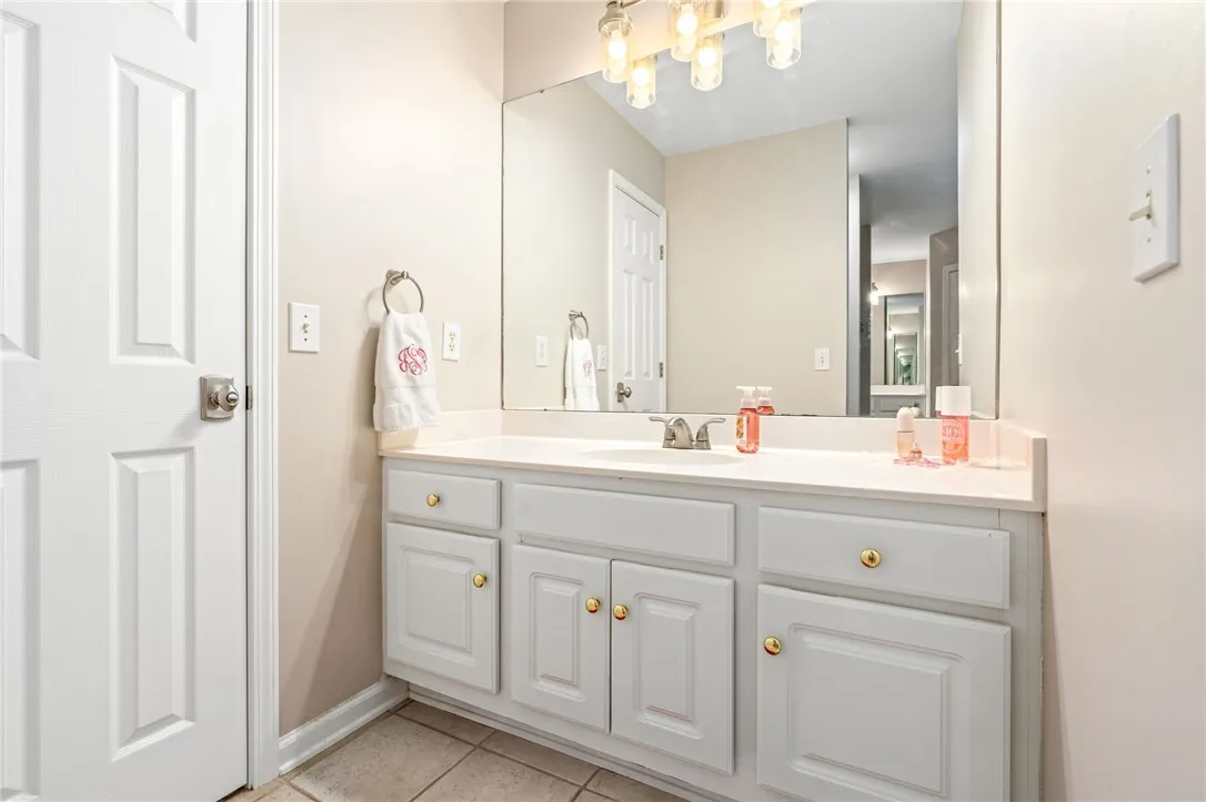 A classic white vanity sits below a large wall mirror in this well-appointed bathroom.