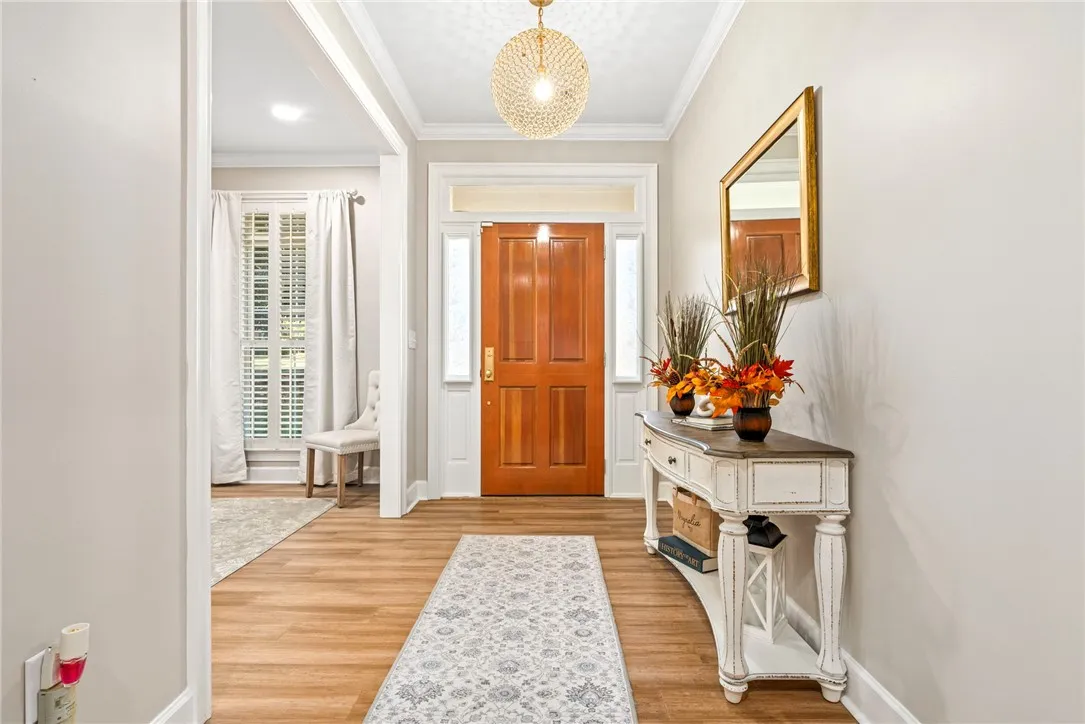 An inviting entryway showcases warm wood flooring, elegant crown molding, and a classic paneled front door.