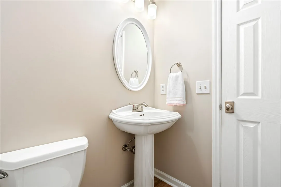 An elegant pedestal sink sits beneath an oval mirror in this classic powder room.