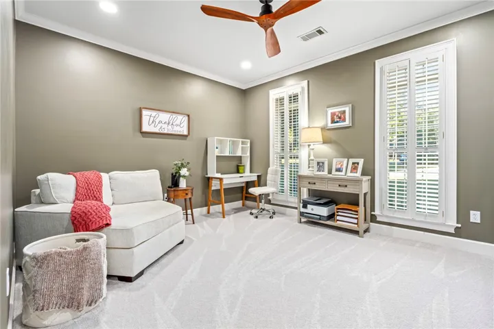 Crown molding and plantation shutters frame a versatile space featuring plush carpeting and recessed lighting.