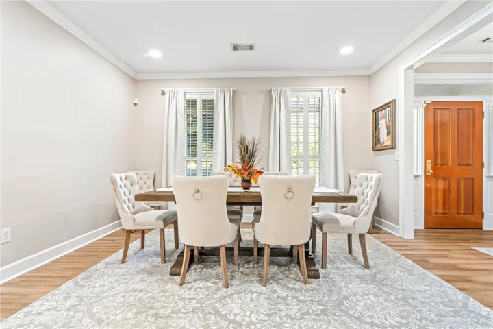 Elegant crown molding complements clean lines and warm wood-style flooring in this classic dining space.