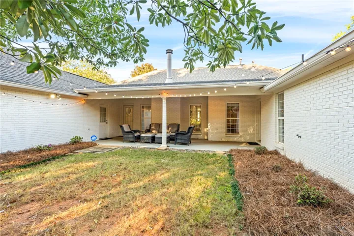 A covered back patio overlooks the yard, framed by classic painted brick walls.