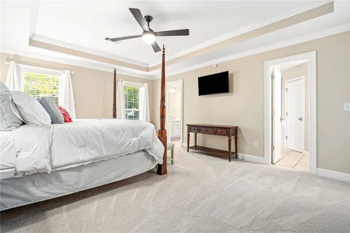 Soft carpeting pairs with a detailed tray ceiling to create a serene primary suite retreat.