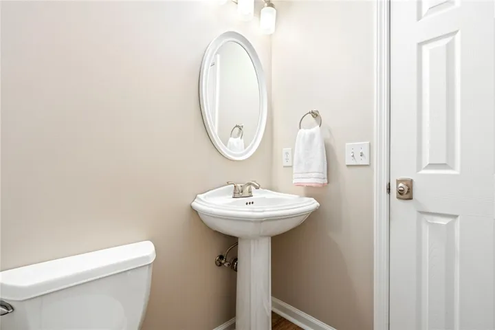 An elegant pedestal sink sits beneath an oval mirror in this classic powder room.
