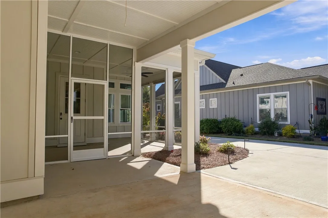 A sheltered concrete patio connects the main structure to an adjacent paved driveway.