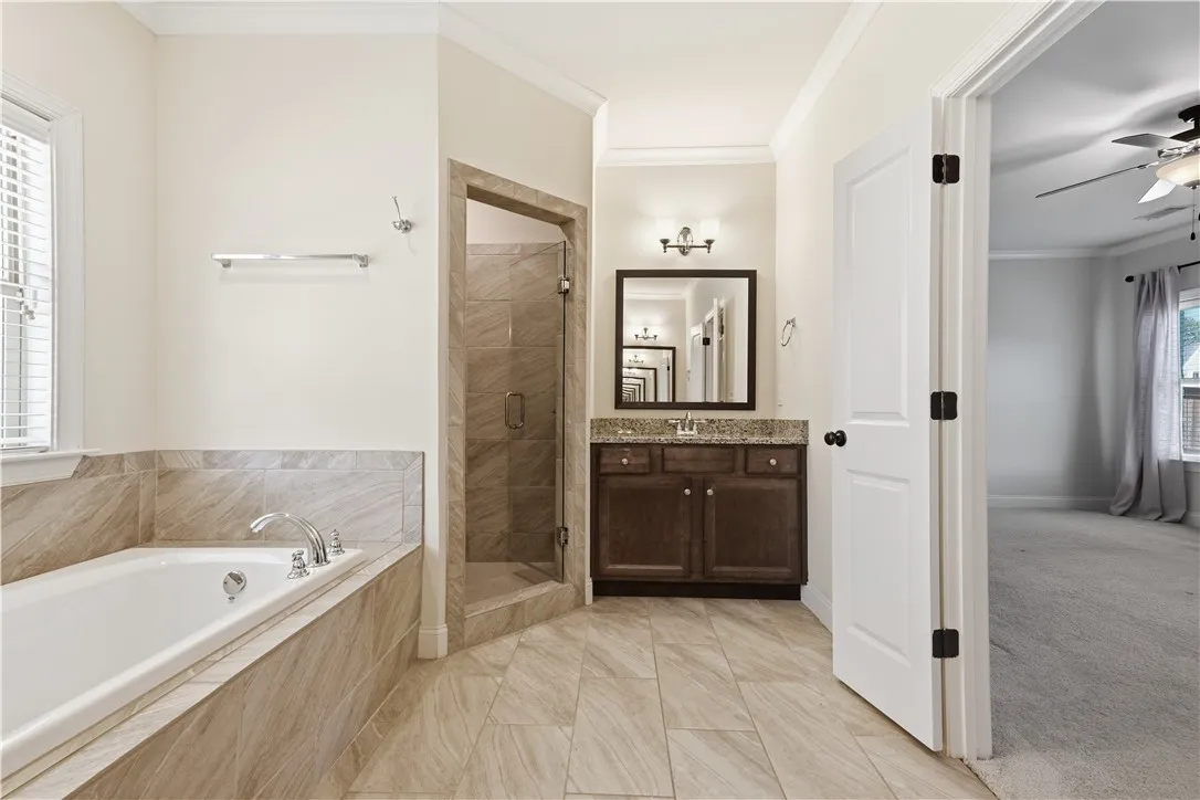 A classic primary bathroom features a tiled soaking tub and a separate tile shower with a frameless glass door.