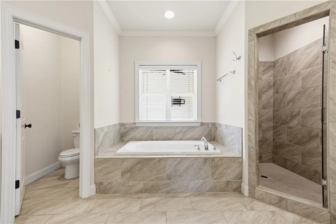 A large soaking tub is positioned under a window in the primary bath.