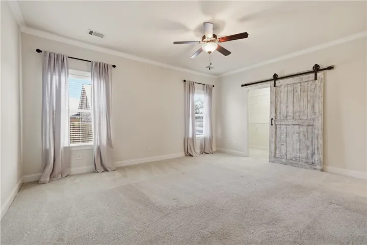 A barn door ads an architectural element to the primary bedroom.