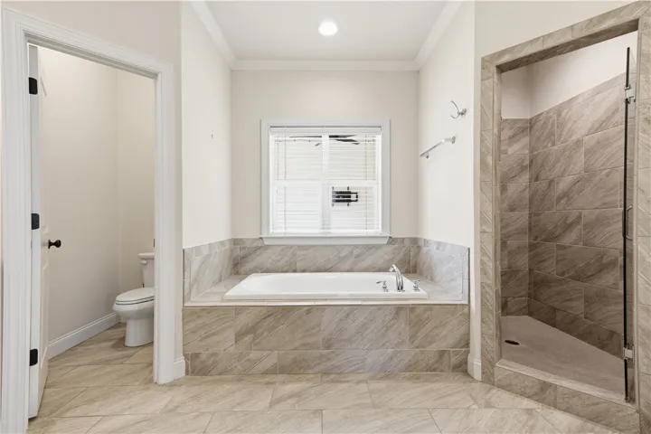 A large soaking tub is positioned under a window in the primary bath.