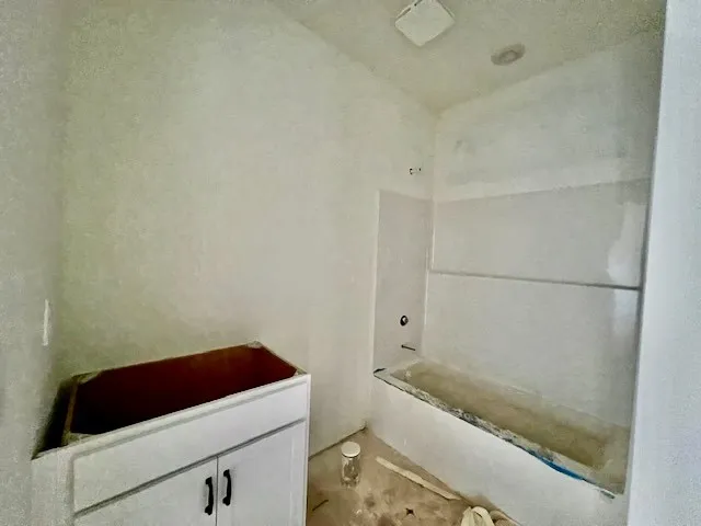 An unfinished bathroom highlights a built-in bathtub paired with clean tile surround details.