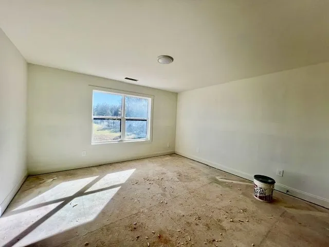 Natural light streams through a large double window into this spacious bedroom awaiting custom finishes.