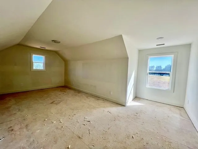 Sloped ceilings frame this unfinished upper-level space filled with natural light from dual windows.