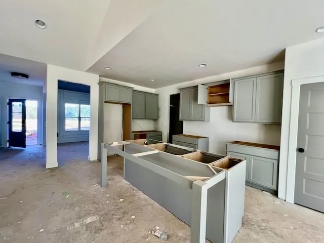 A spacious kitchen space under construction features a large island frame and recessed lighting.