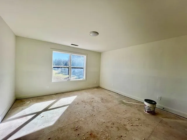 Natural light streams through a large window into this unfinished room awaiting your final flooring choice.