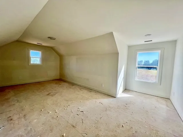 Angled ceilings and multiple windows define this versatile upper-level space currently under construction.